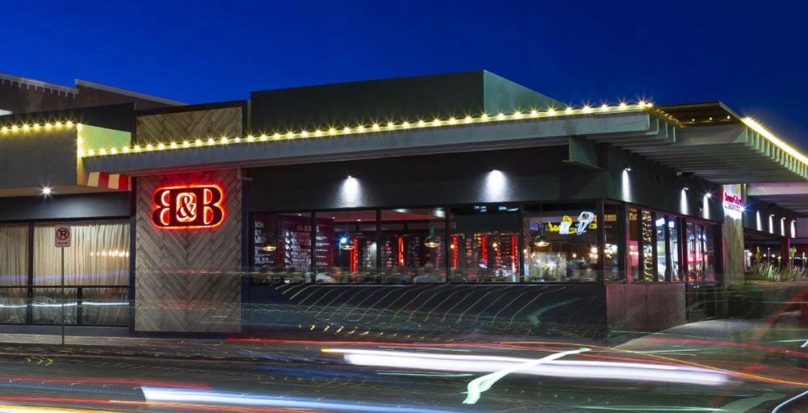Completed commercial holiday lighting with warm white lights outlining a restaurant’s roofline at dusk