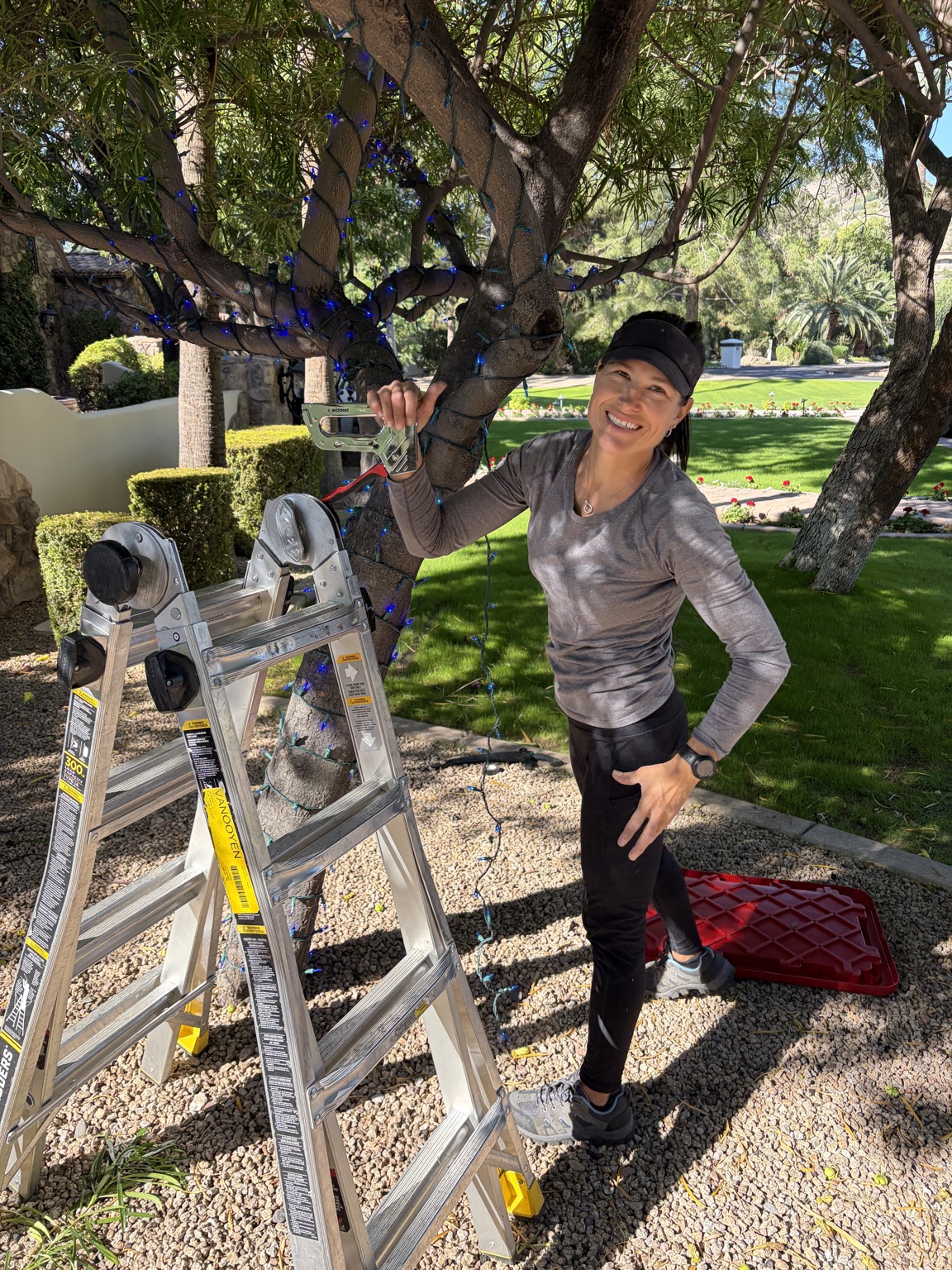 Jodie smiling beside a ladder during an outdoor lighting installation