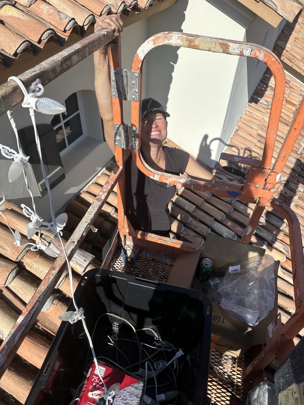 Jodie working from a lift beside a tile roof during lighting installation